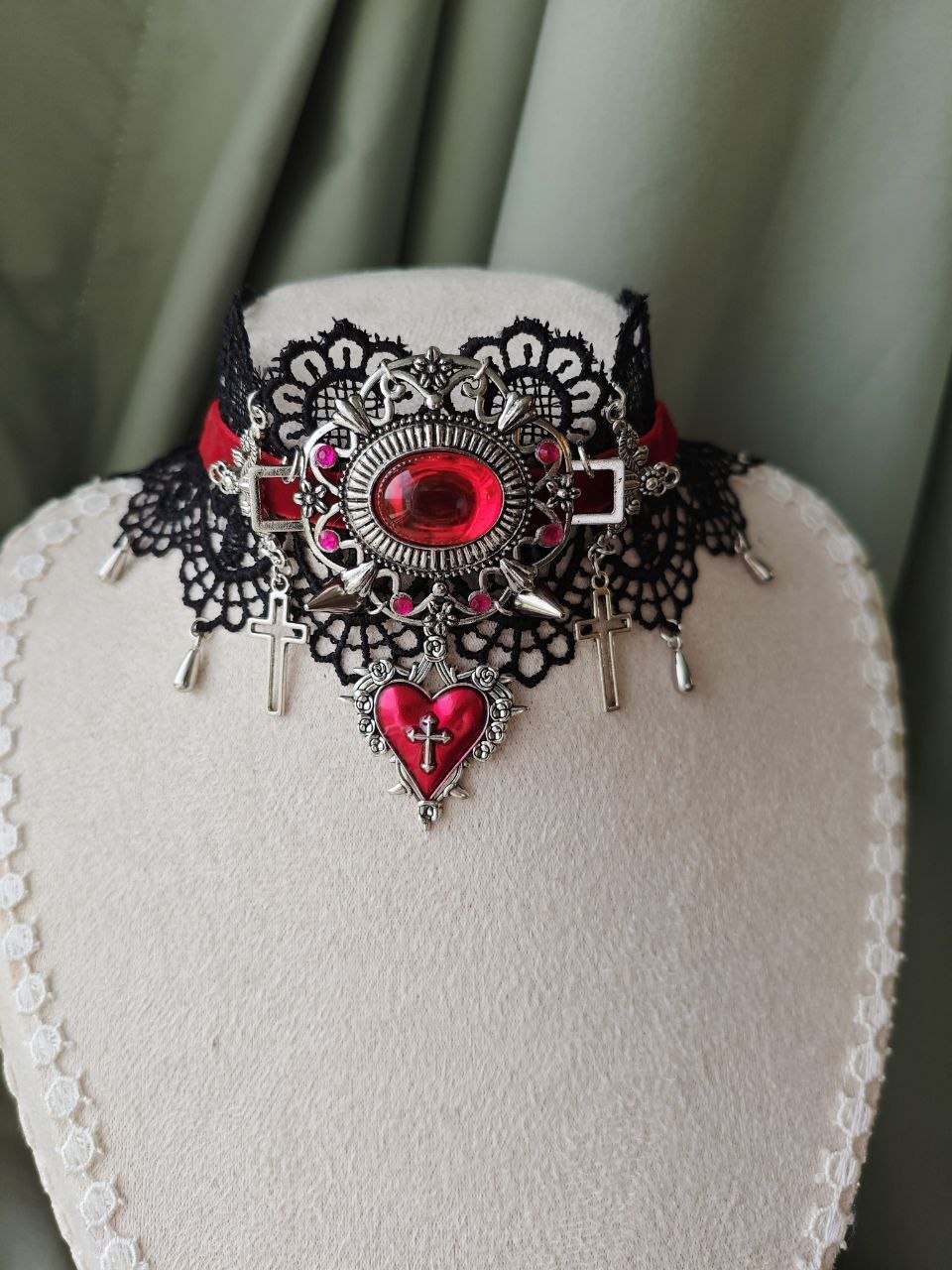 Close-up of Midnight Martyr gothic choker with red jewel and cross charms