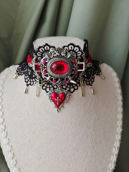 Close-up of Midnight Martyr gothic choker with red jewel and cross charms